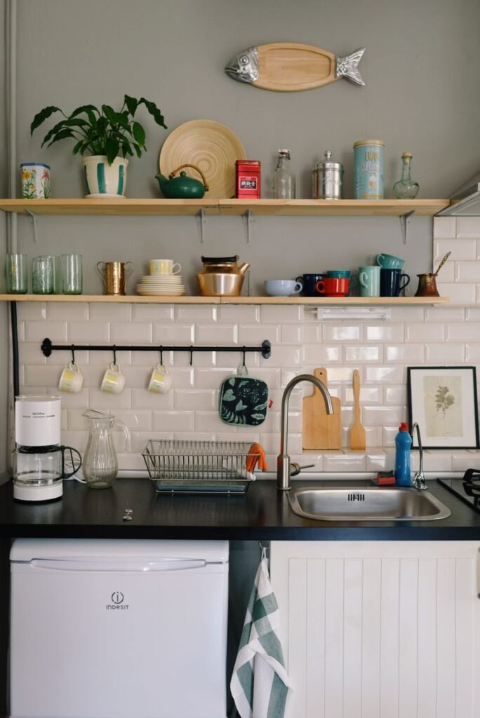 Small kitchen storage ideas for apartments: open wooden floating shelves holding bowls and glasses in a kitchen