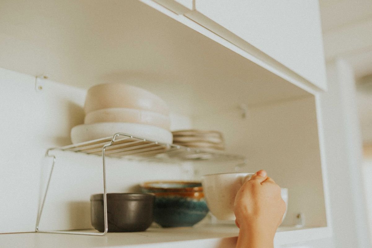 Kitchen cabinet organization ideas: a wire shelf riser inside a cabinet doubling space for bowls, plates and mugs.