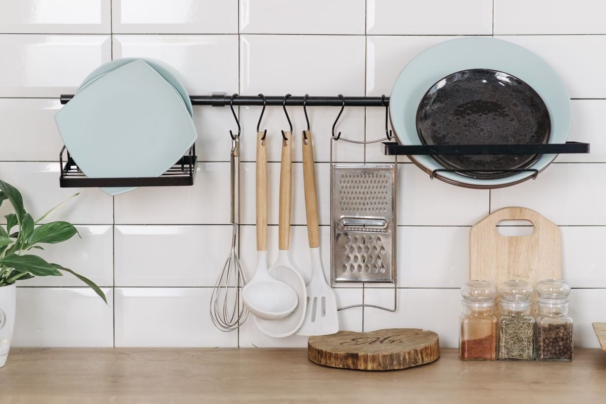 Kitchen cabinet organization ideas: utensils hanging from a wall rail with hooks beside the cabinets, freeing drawer space.