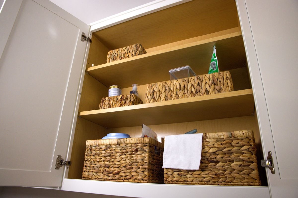 Kitchen cabinet organization ideas: like items grouped in wicker baskets inside a cabinet so they pull out like drawers.