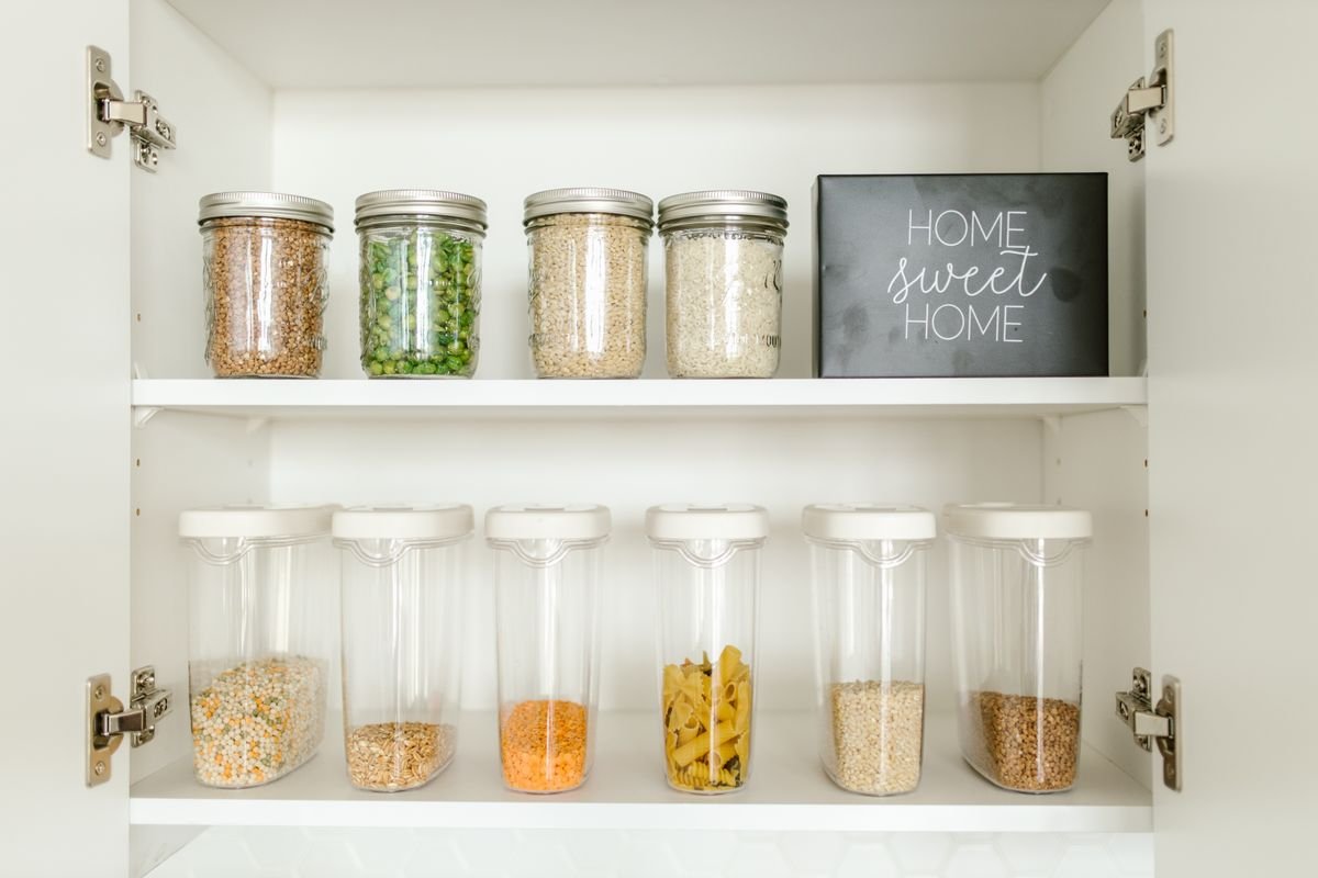 Kitchen cabinet organization ideas: dry goods decanted into neat glass and plastic jars lined up inside a cabinet.
