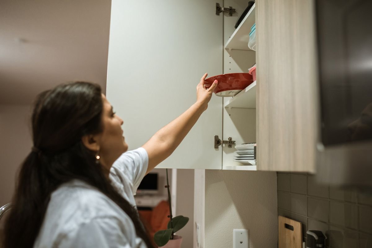 Kitchen cabinet organization ideas: a woman putting a bowl back in place during a quick monthly cabinet reset.