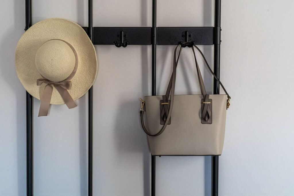 Small bedroom storage ideas no closet: a sun hat and leather handbag hanging on wall hooks for bags and hats