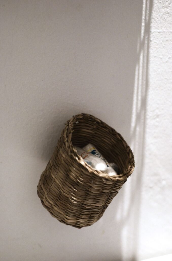 Small bedroom storage ideas no closet: a wicker storage basket hanging on a wall for scarves and socks