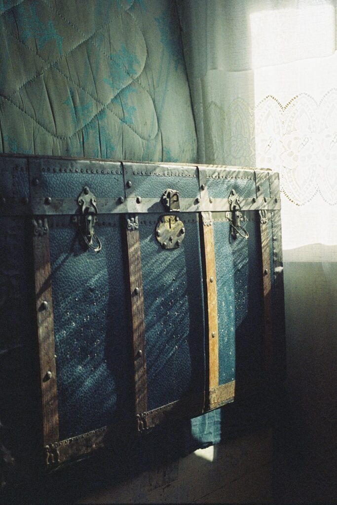 Small bedroom storage ideas no closet: a vintage storage trunk with wooden accents used as decor for blanket storage