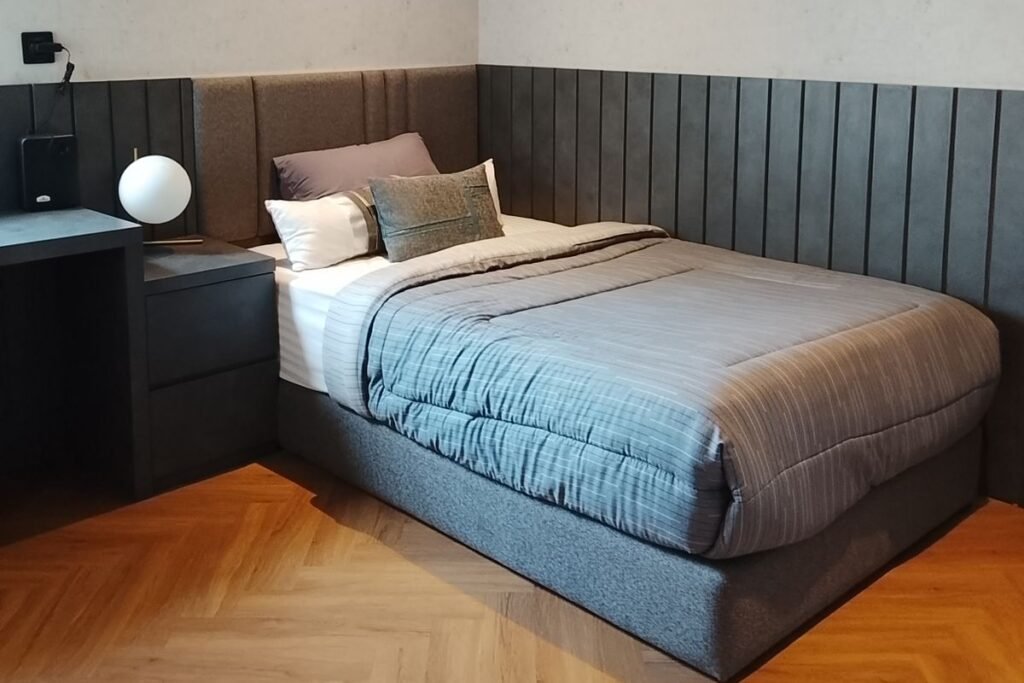 Bed placed in the quietest corner of a studio apartment layout, away from the door and the living zone