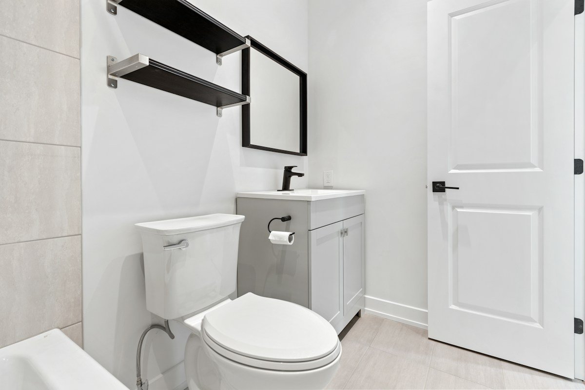 Small bathroom storage ideas no counter space: black floating shelves mounted on the wall above a toilet in a small bathroom