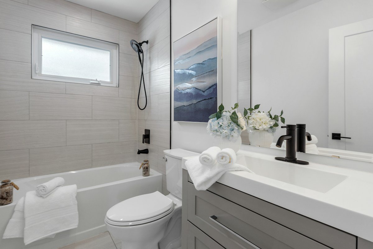 Small bathroom storage ideas no counter space: a bright small bathroom with a bathtub, toilet, and gray vanity with rolled towels