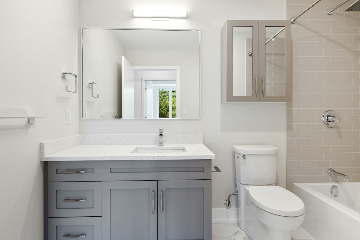 Small bathroom storage ideas no counter space: a gray vanity with a mirrored medicine cabinet mounted on the wall